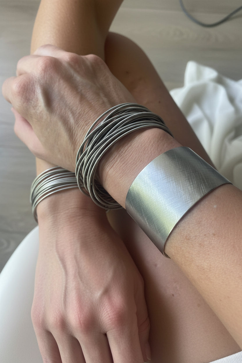 Accumulation de bracelets ressort argentés créant un effet manchette élégant