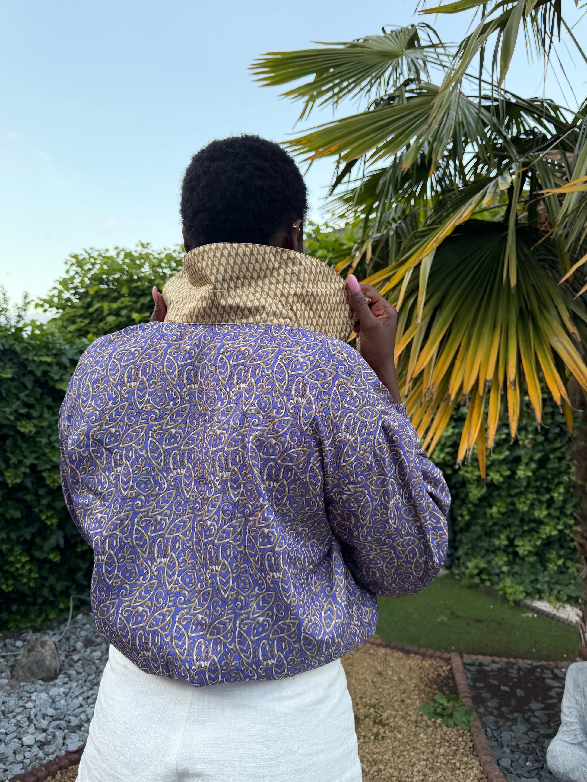 Vue arrière d'un bomber en sari recyclé violet floral porté avec un col doré contrastant