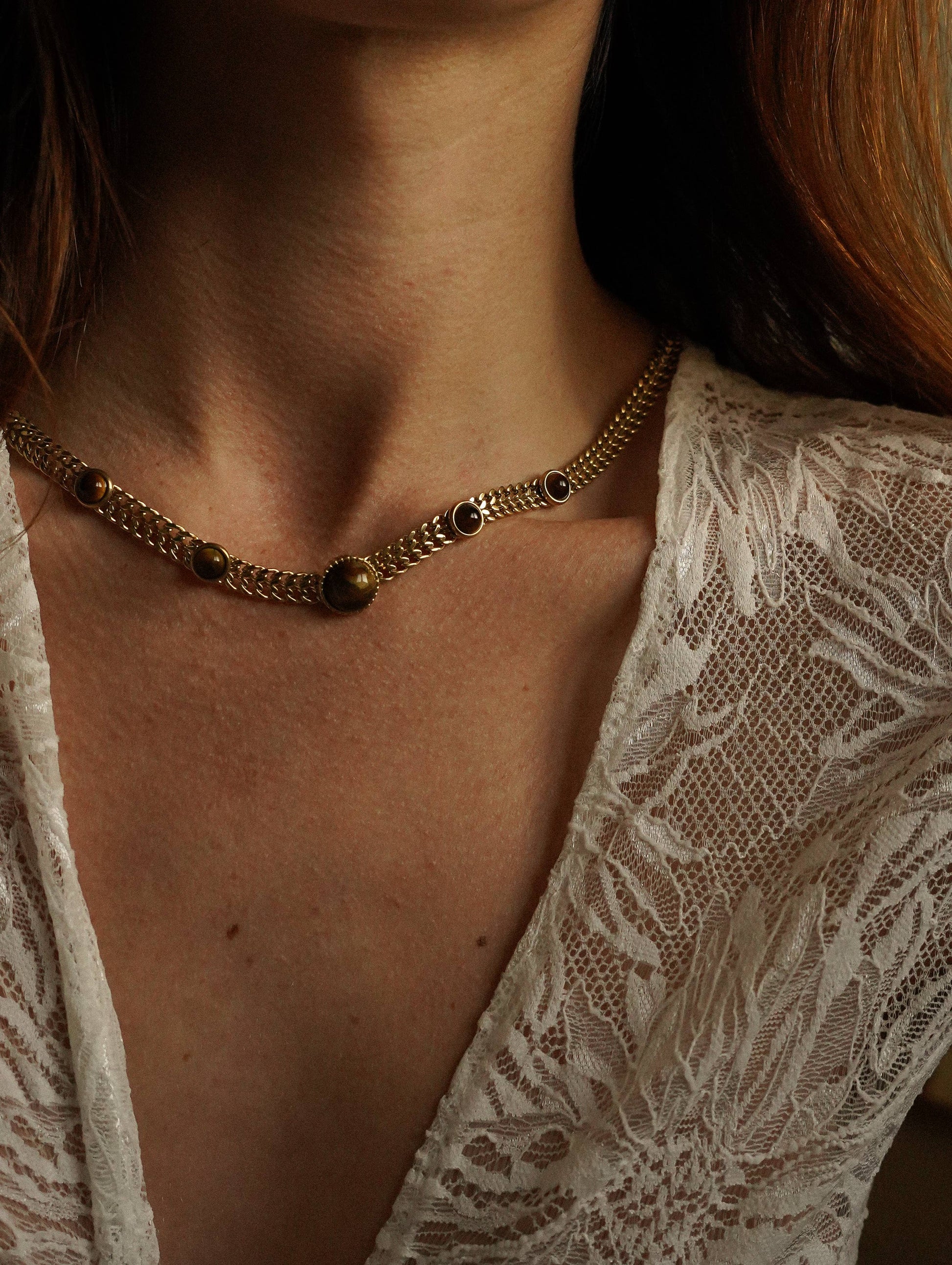 Femme portant un collier cabochons marron sur chaîne gourmette large en acier inoxydable doré.
