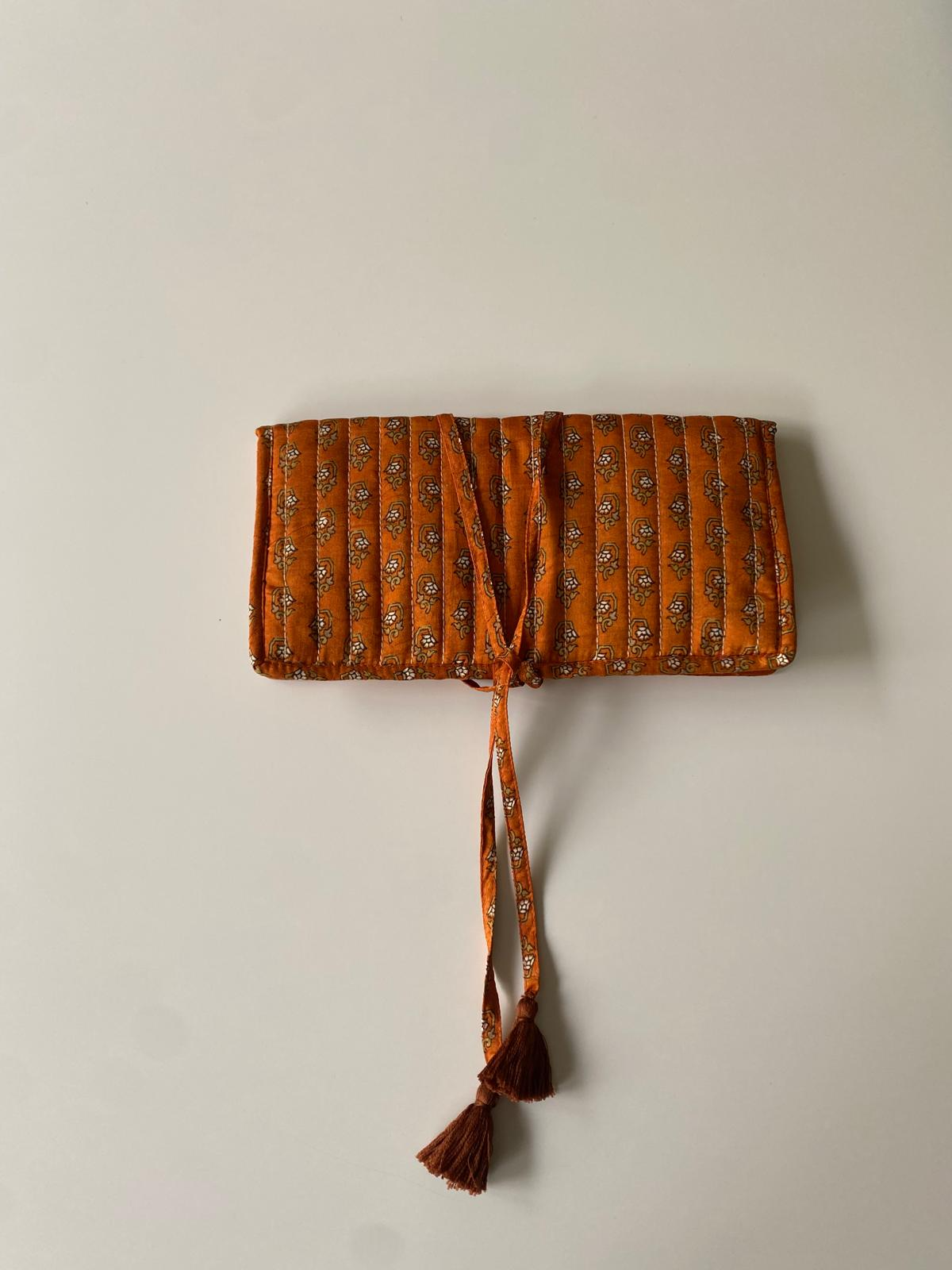 Détail du tissu en sari recyclé ocre et terracotta utilisé pour la confection artisanale de la pochette