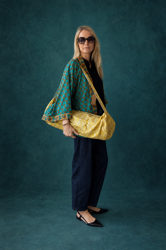 Femme portant à l’épaule un sac de yoga jaune et blanc en sari indien recyclé.