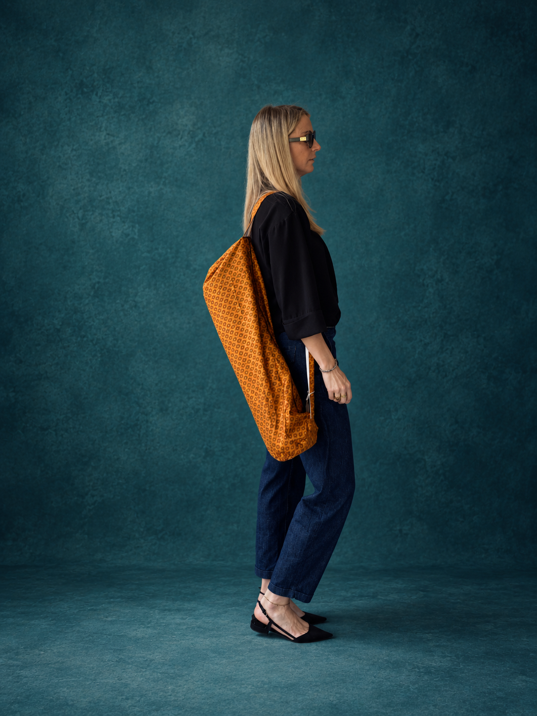 Femme portant à l’épaule un sac de yoga en sari indien recyclé orange et bordeaux.