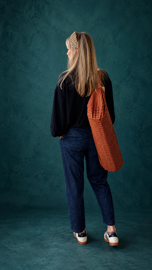 Femme portant dans le dos un sac de yoga en sari indien recyclé orange, bordeaux et brun.